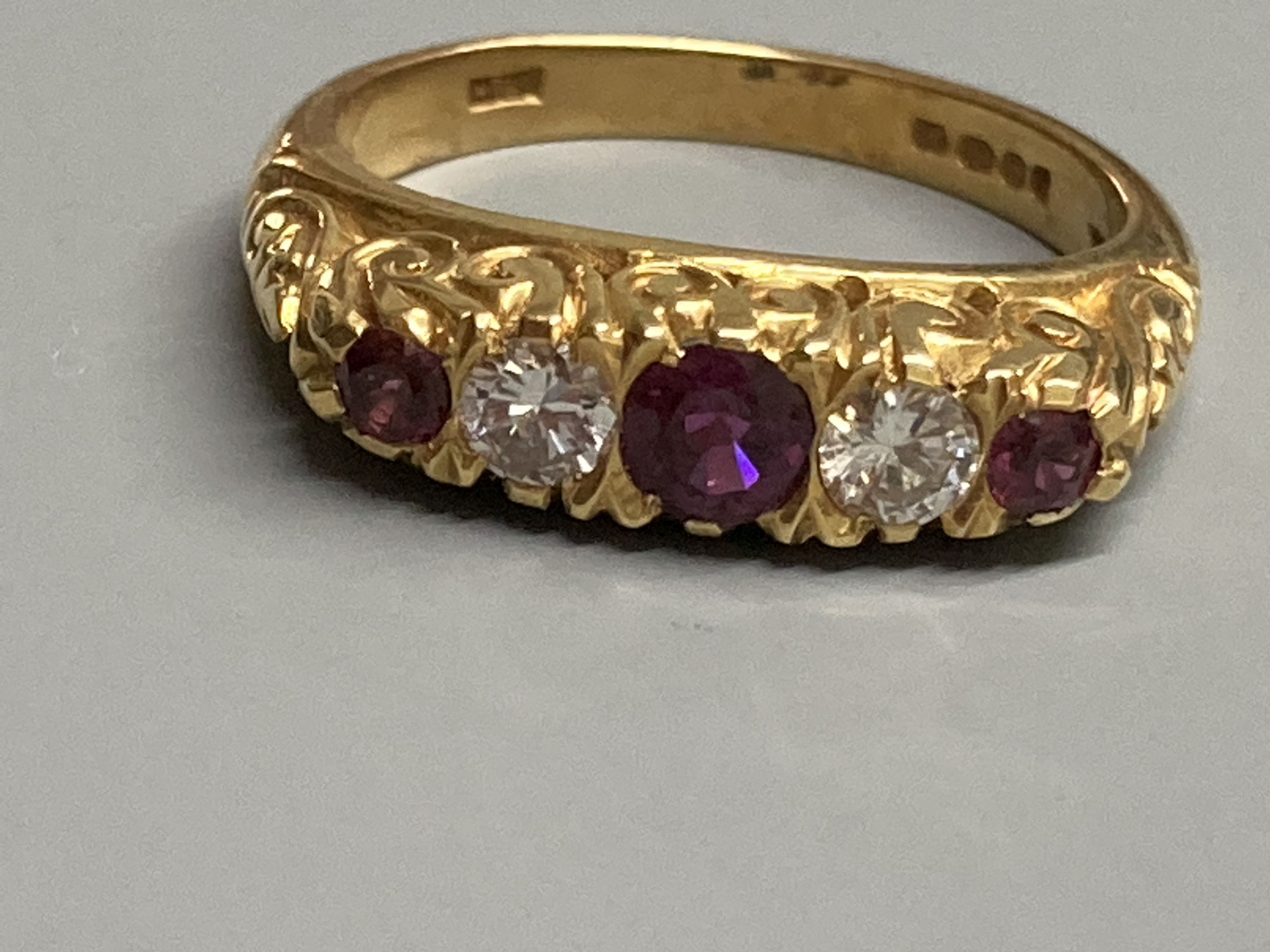 A modern Victorian style 18ct gold, three stone ruby and two diamond set half hoop ring, size N, gross 6.2 grams.